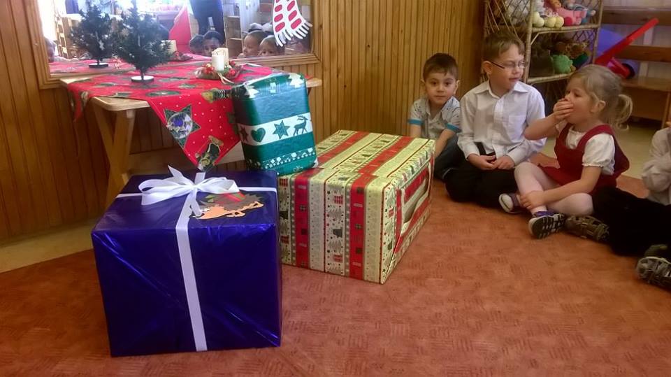 Óvodások ajándékcsomagok előtt ülnek