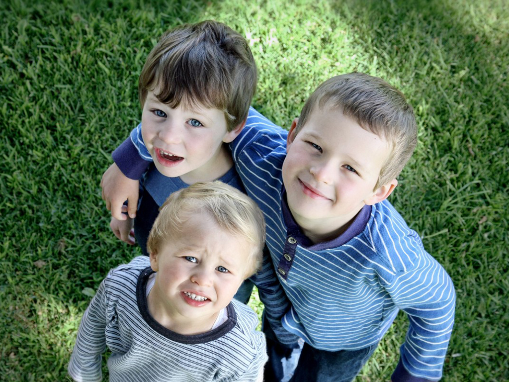 Három kisgyermek néz felfelé a fényképező felé